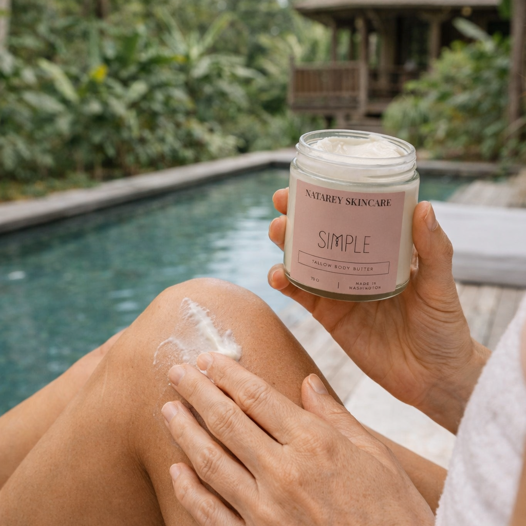 Person applying cream to their leg by a pool with a tropical setting